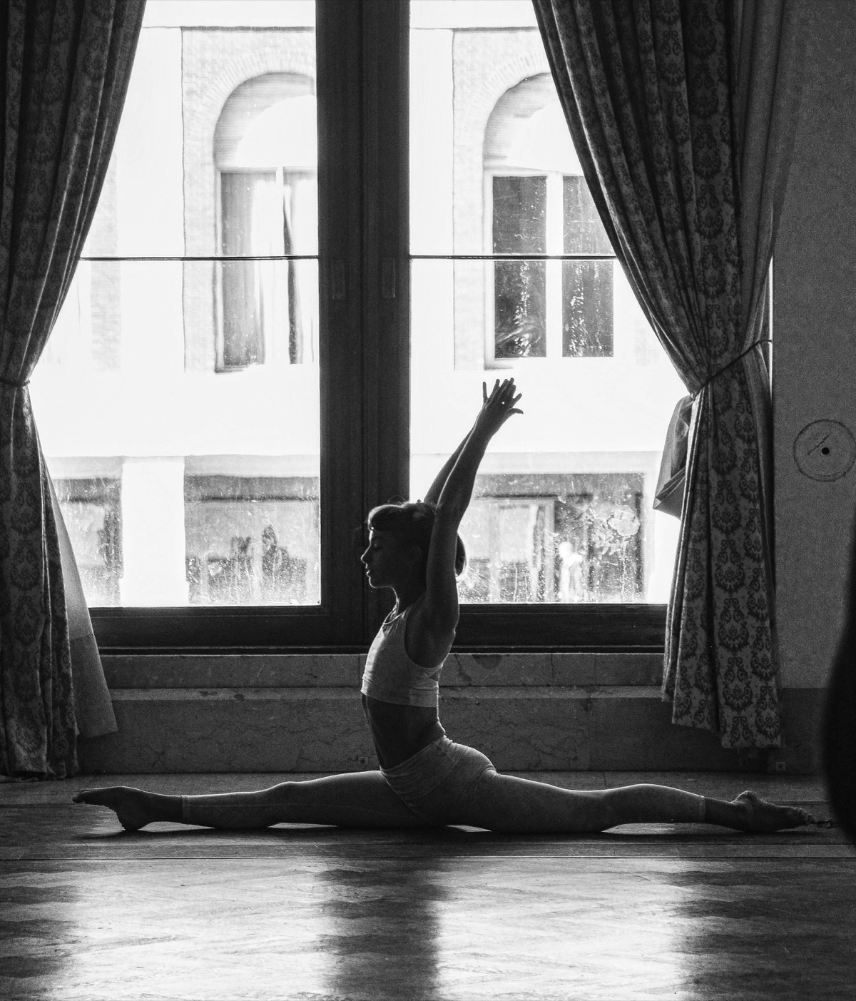 Mujer realizando split en silueta frente a una ventana